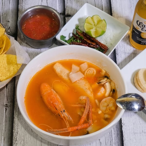 Seafood soup with shrimp, squid, and mussels, served with chips, salsa, lime, and a Corona.